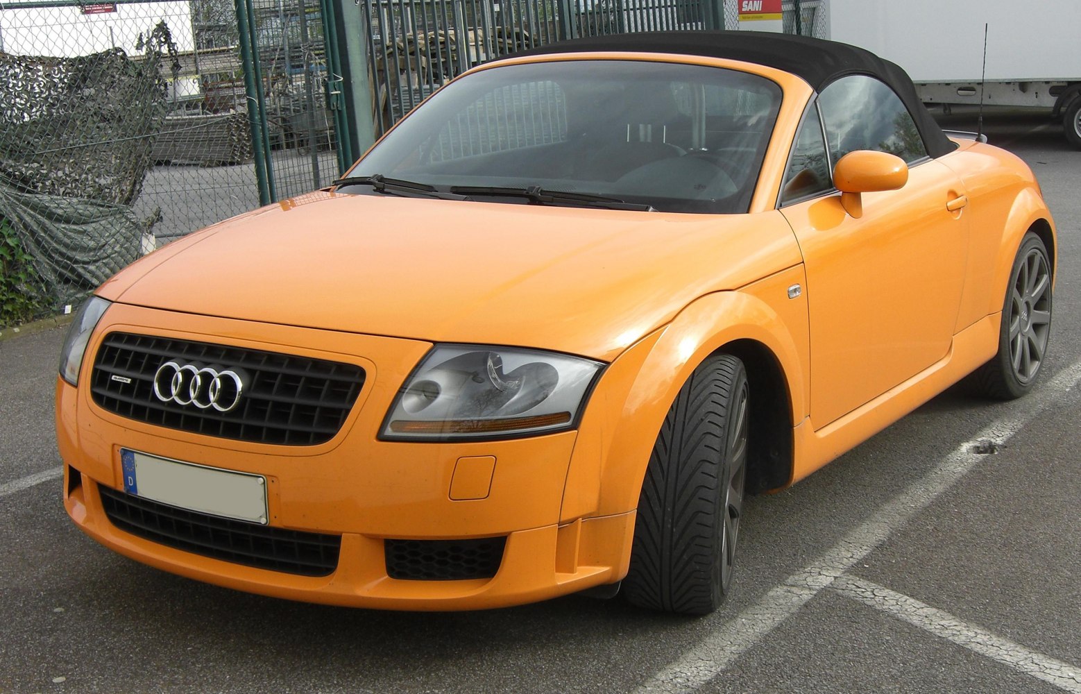 Front view orange convertible with black soft top and sporty wheels
