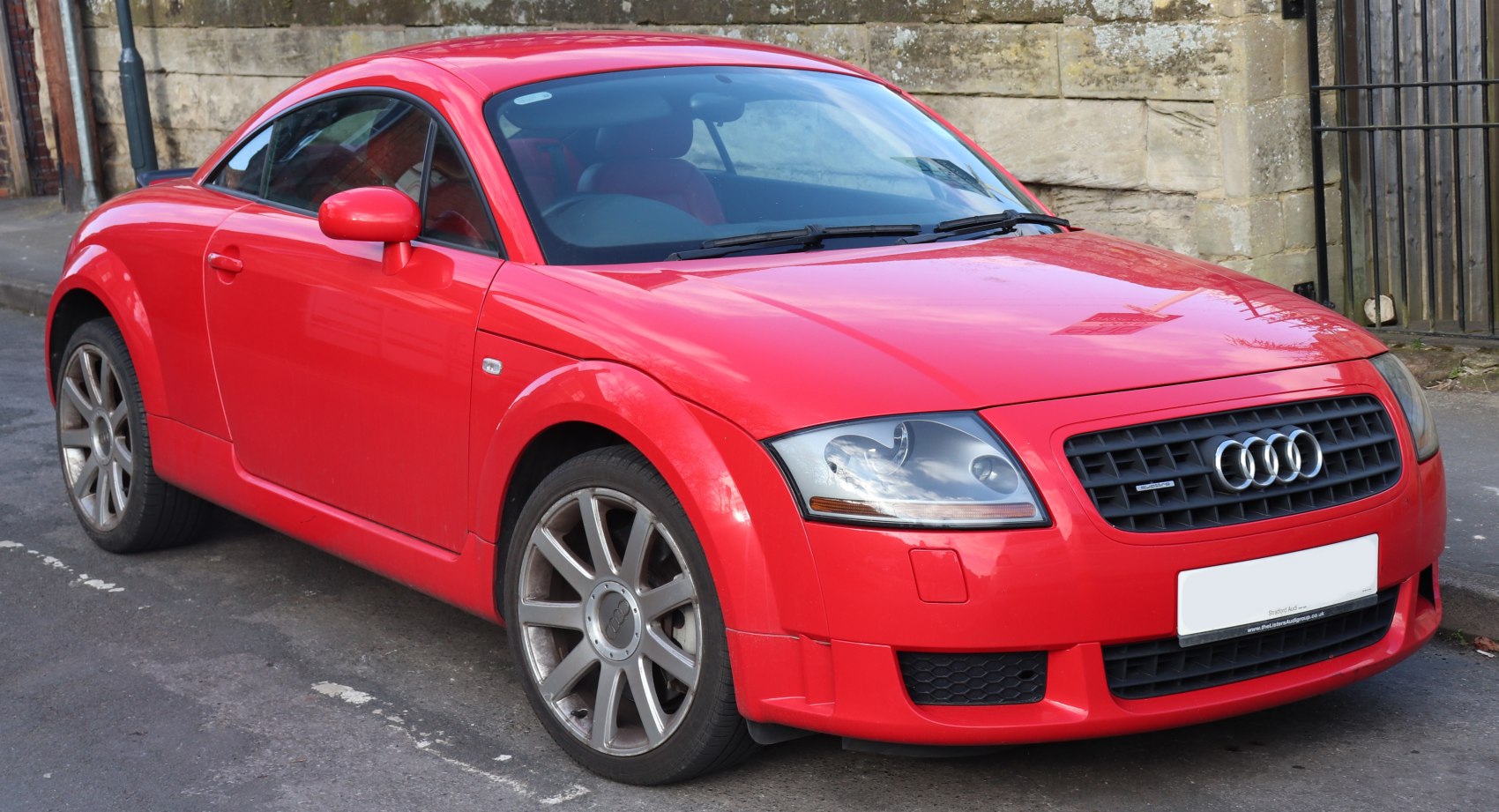 Front side view of red coupe with alloy wheels and distinctive headlamps