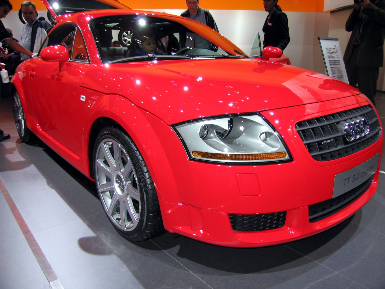 Front view with headlights, grille, and alloy wheel of a red sports coupe