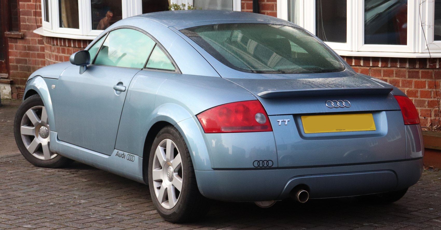 Rear and side profile of light blue compact coupe with distinct spoiler and taillights.