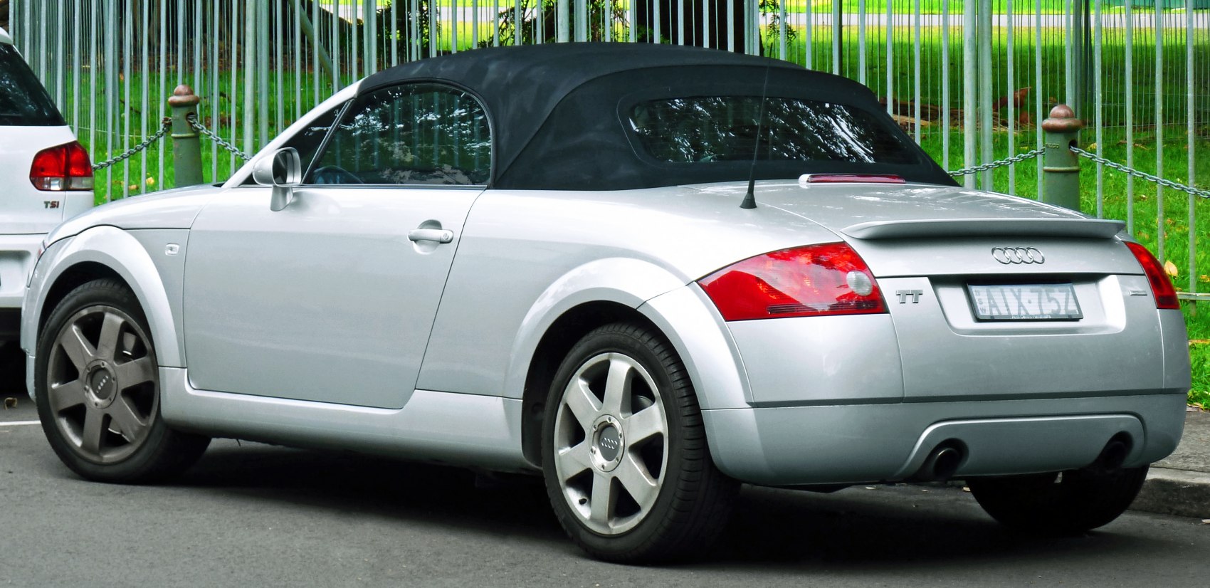 Silver convertible with soft top, sporty rear, alloy wheels, and spoiler