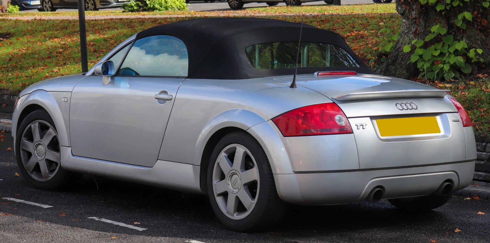 Silver convertible roadster with soft top and rear dual exhaust