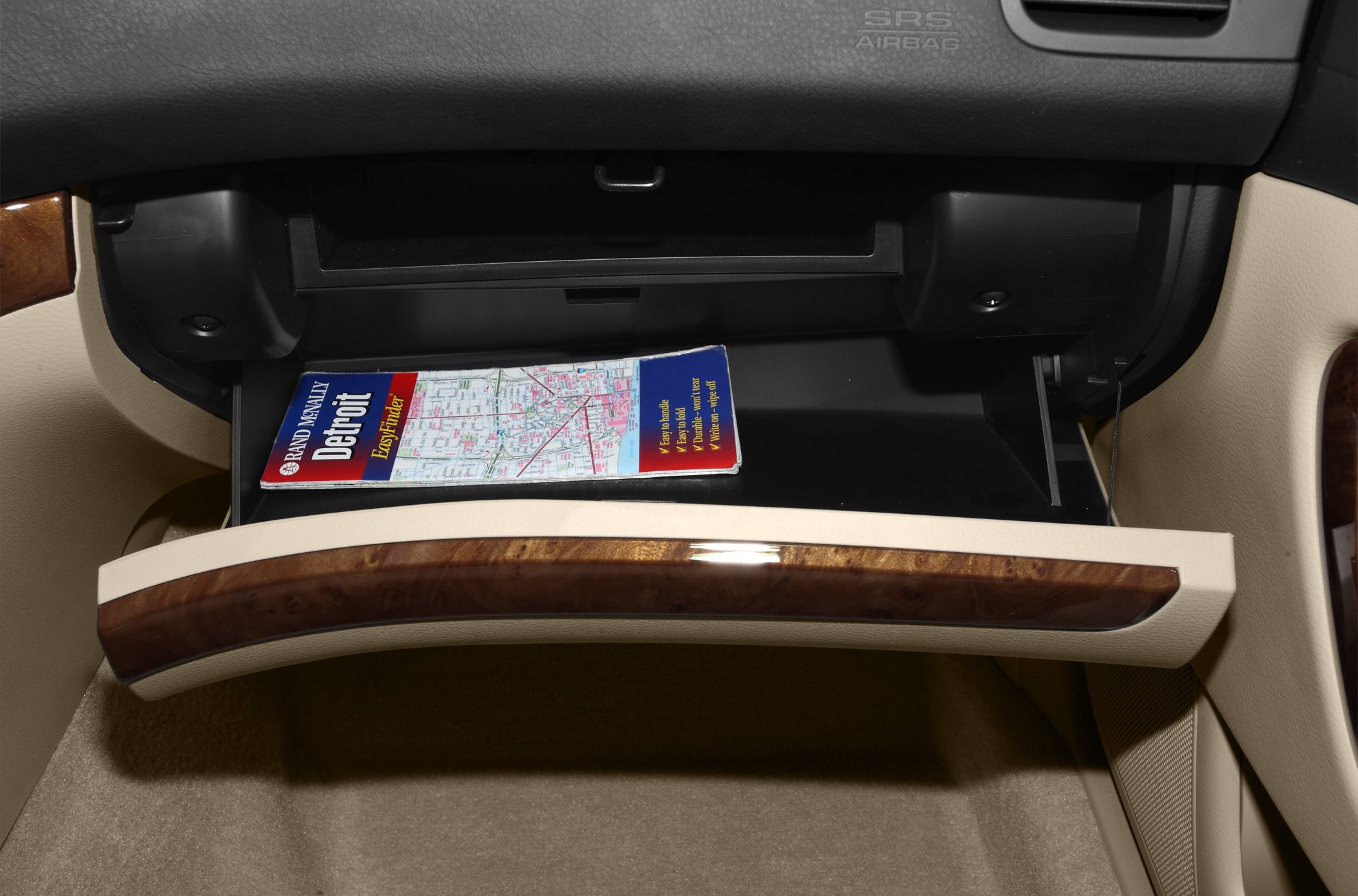Open glove compartment with wood trim and a map inside