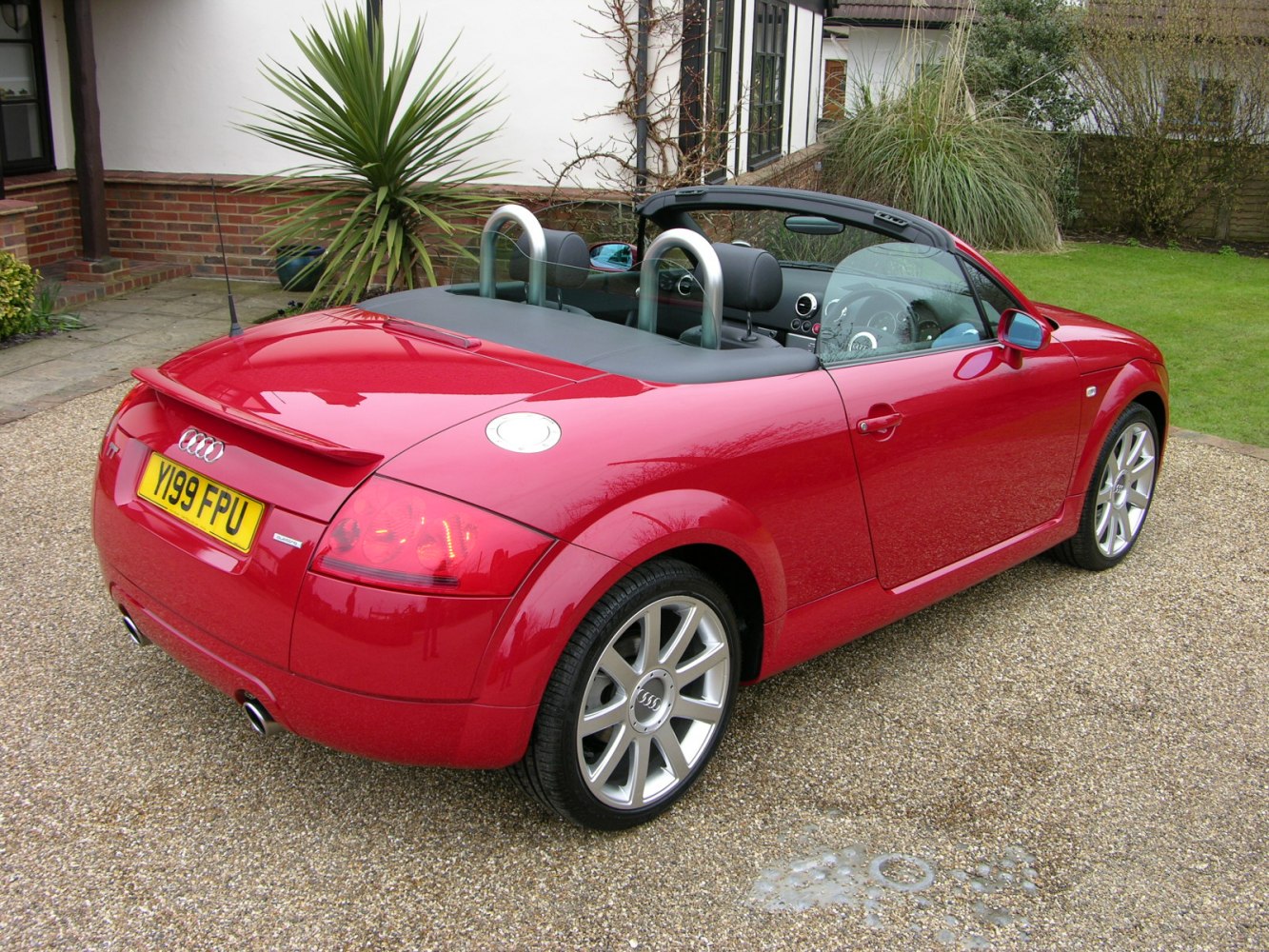 Rear view of red convertible with dual roll bars and integrated spoiler