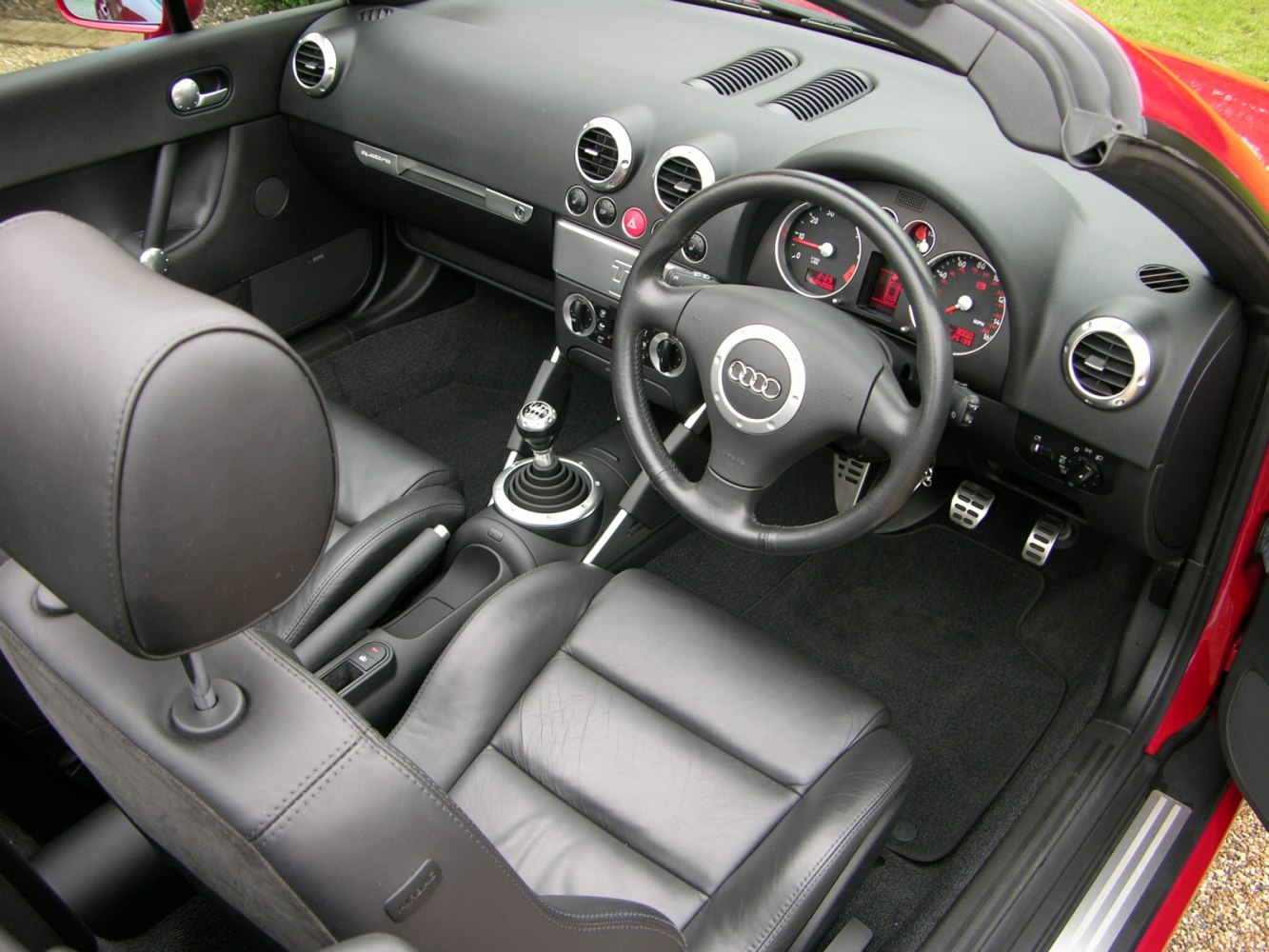 Dashboard, manual gear shift, black leather seats, steering wheel