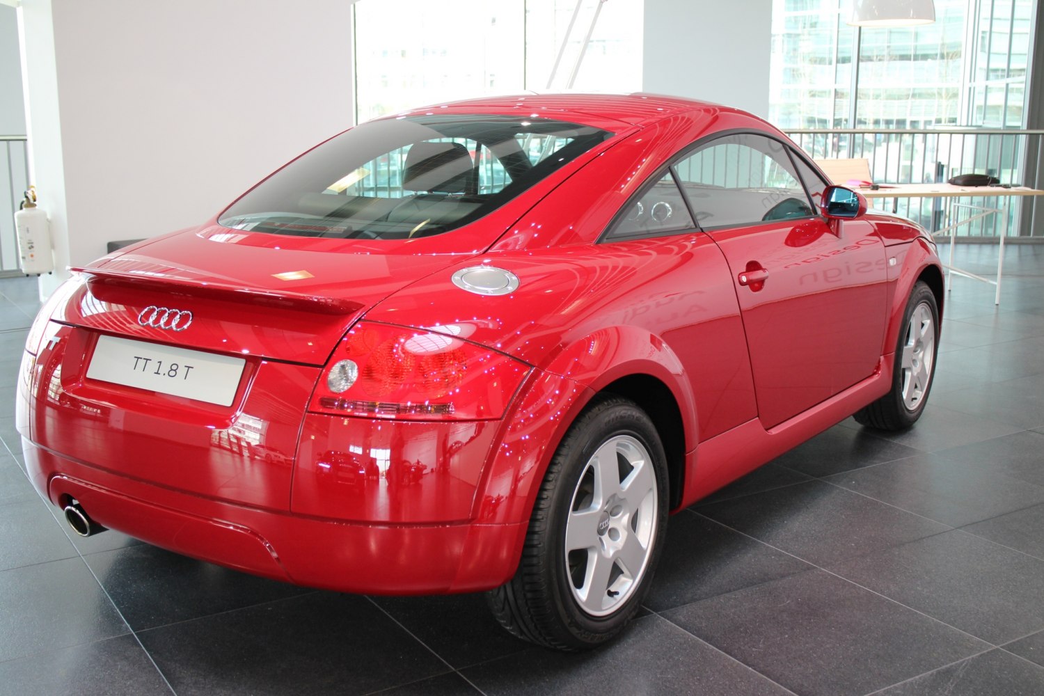 Red sports coupe rear with curved hatch, distinct tail lights, and visible fuel cap.