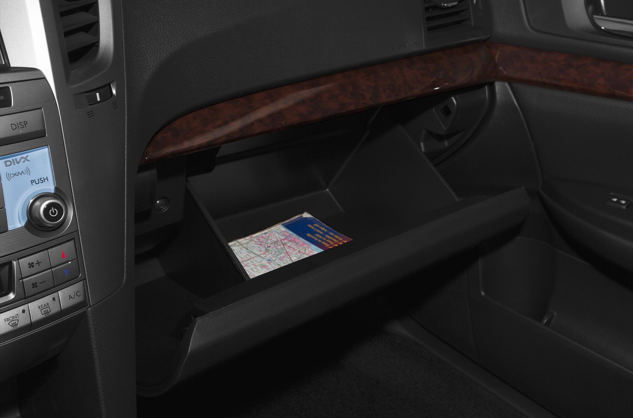 Open glove box with wood trim and adjacent climate control buttons