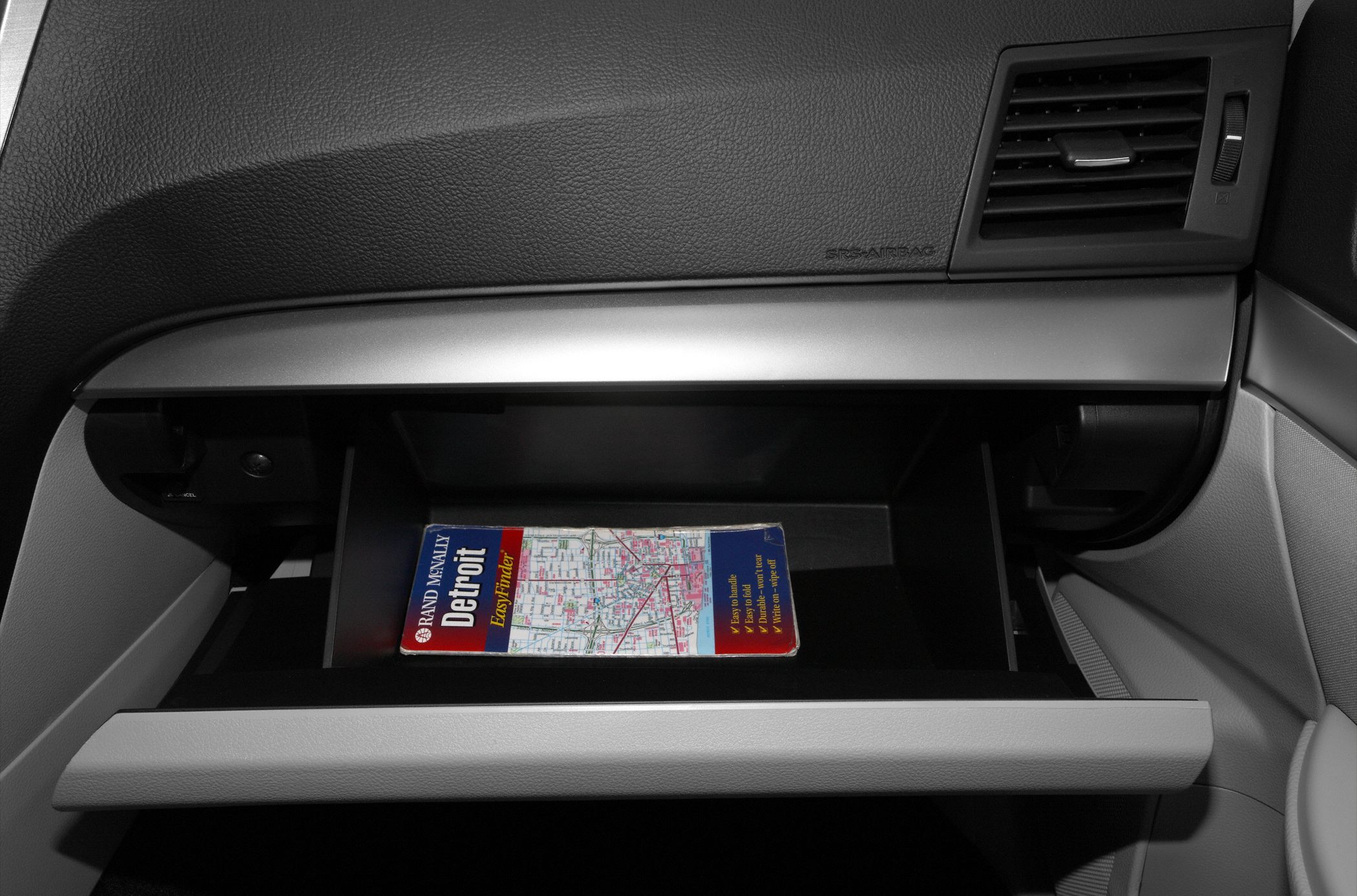 Open glove box with road map inside in vehicle interior