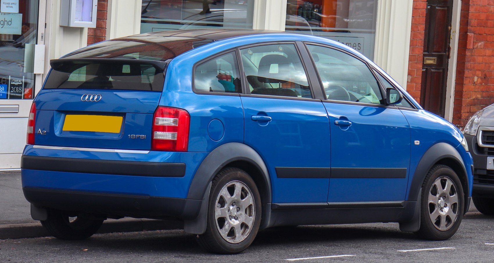 Rear side view of blue compact hatchback with distinctive wheel arches and taillights.