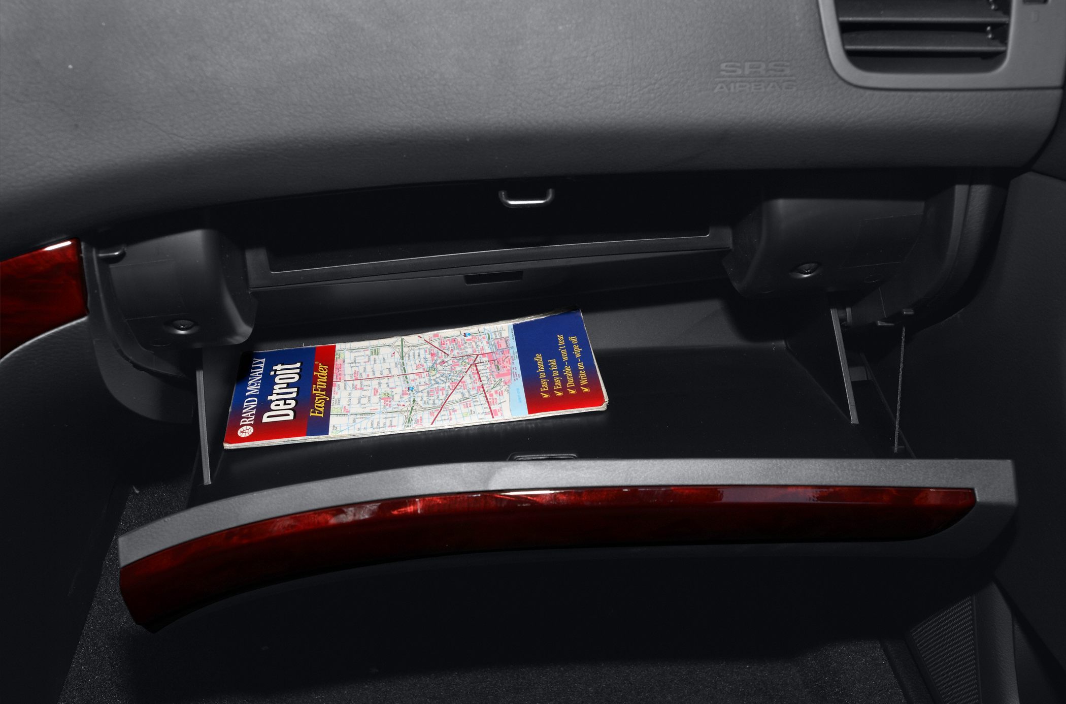 Open glove compartment with wood trim and map inside