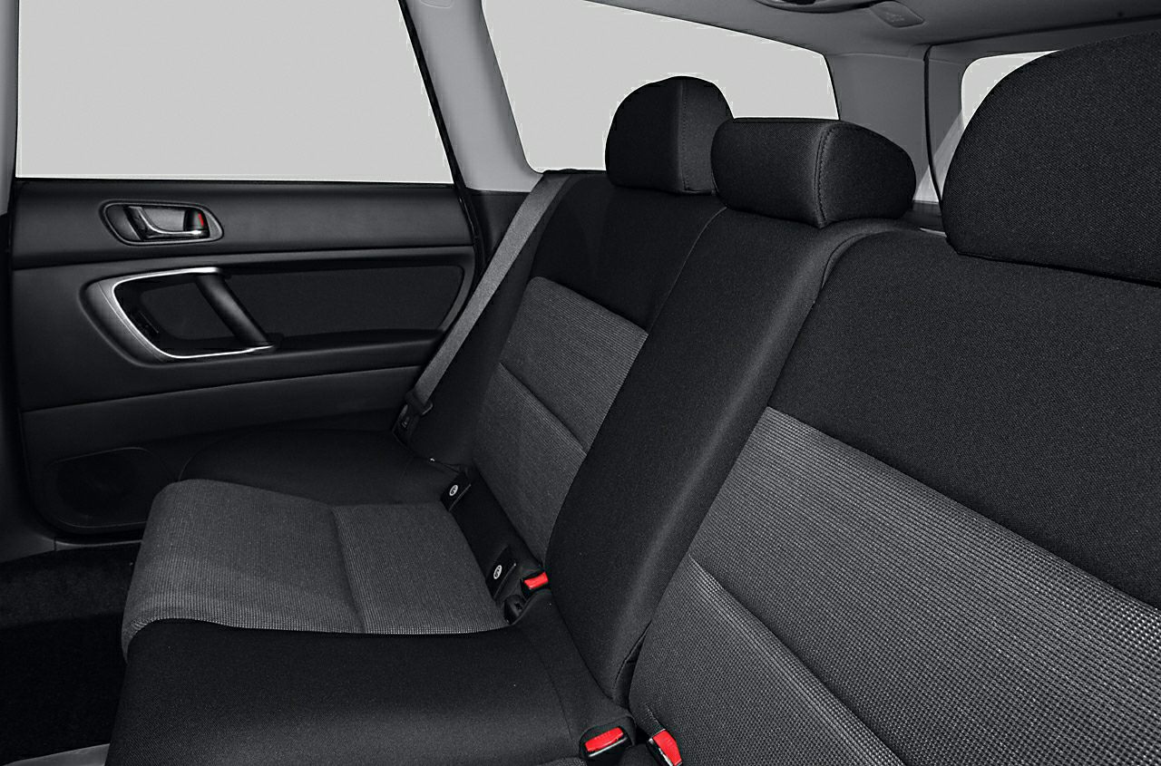 Rear seat interior with black fabric upholstery and red seatbelt buckles.