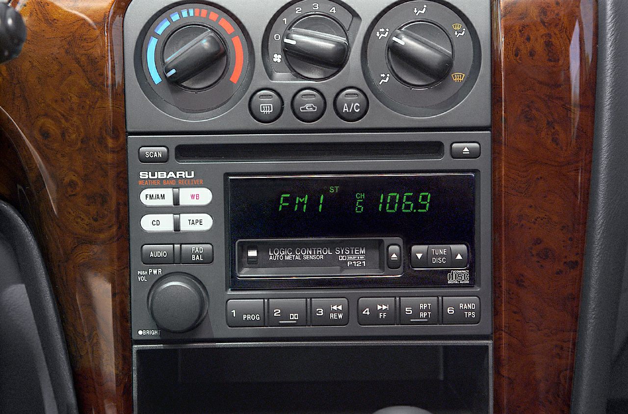 Car radio, tape player, and climate control knobs on wood grain dashboard