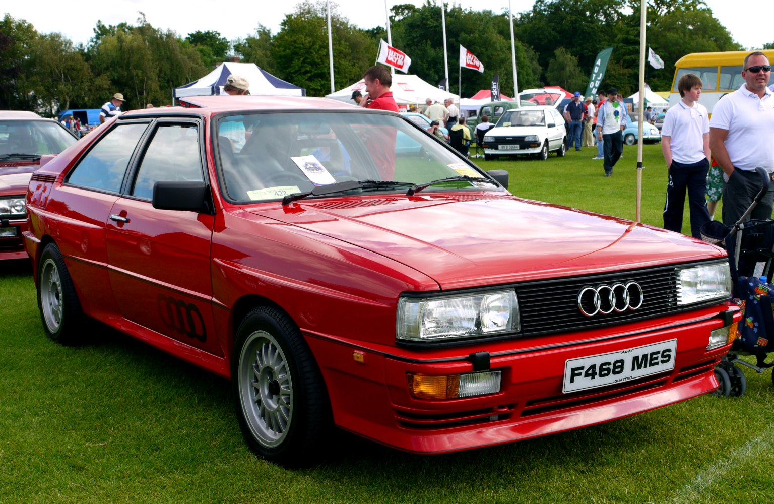 Red 1980s hatchback with boxy design and quad-ring front grille