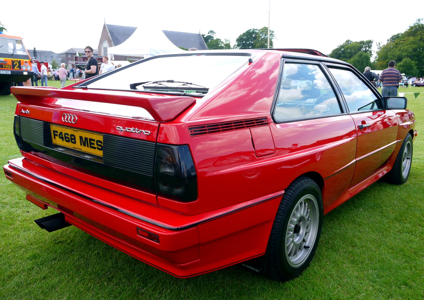 Red sports coupe rear with spoiler and alloy wheels on grass