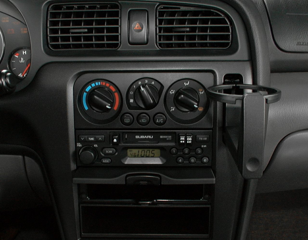 Dashboard with air conditioning controls and stereo system with cup holder.