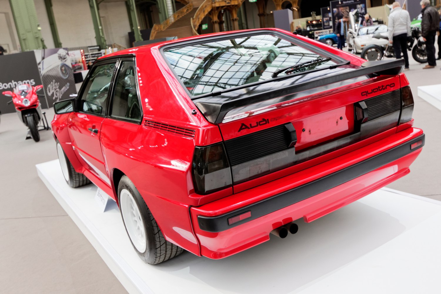 Rear view of a sports car with tinted taillights and a prominent black spoiler
