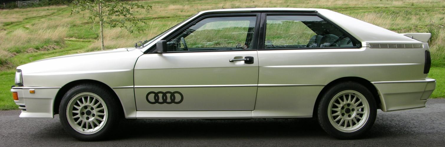 Sleek two-door coupe profile with sporty rear wing and sharp angular body lines.