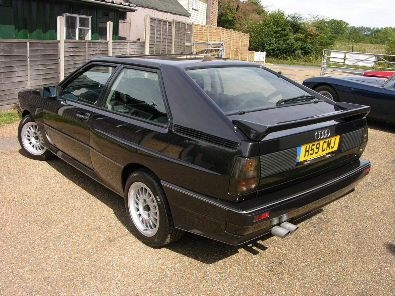 Black hatchback with rear spoiler and dual exhaust pipes