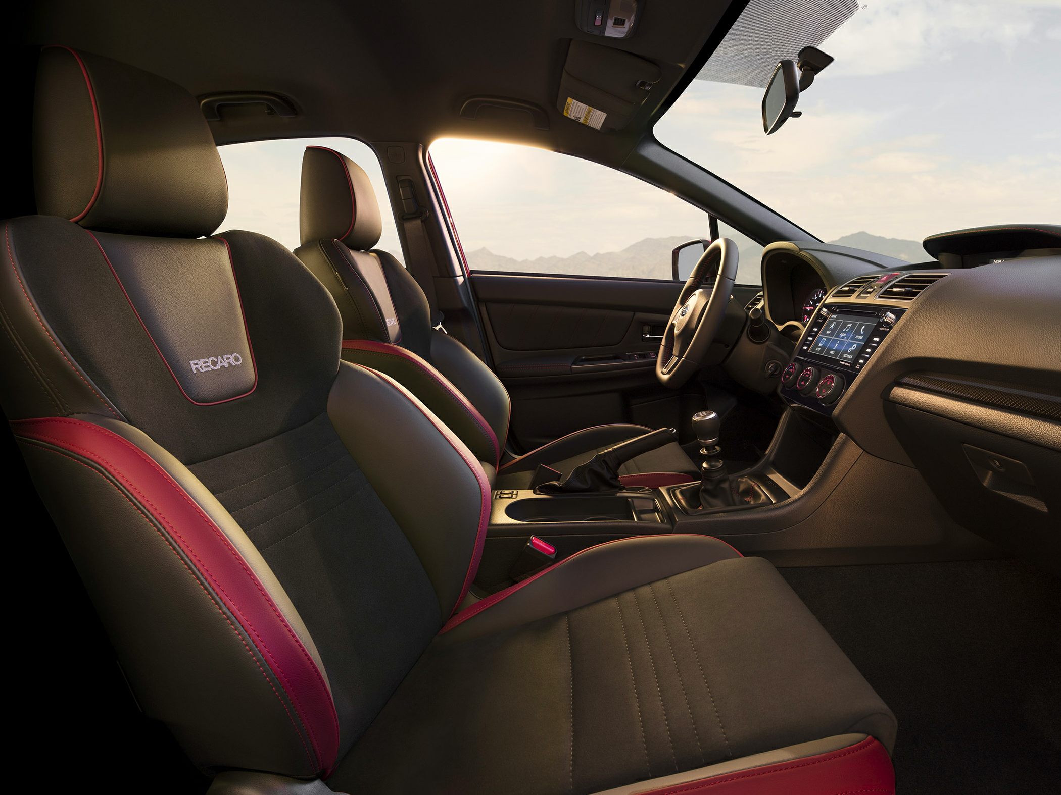 Sporty Recaro seats with red accents and detailed interior in a manual transmission car.