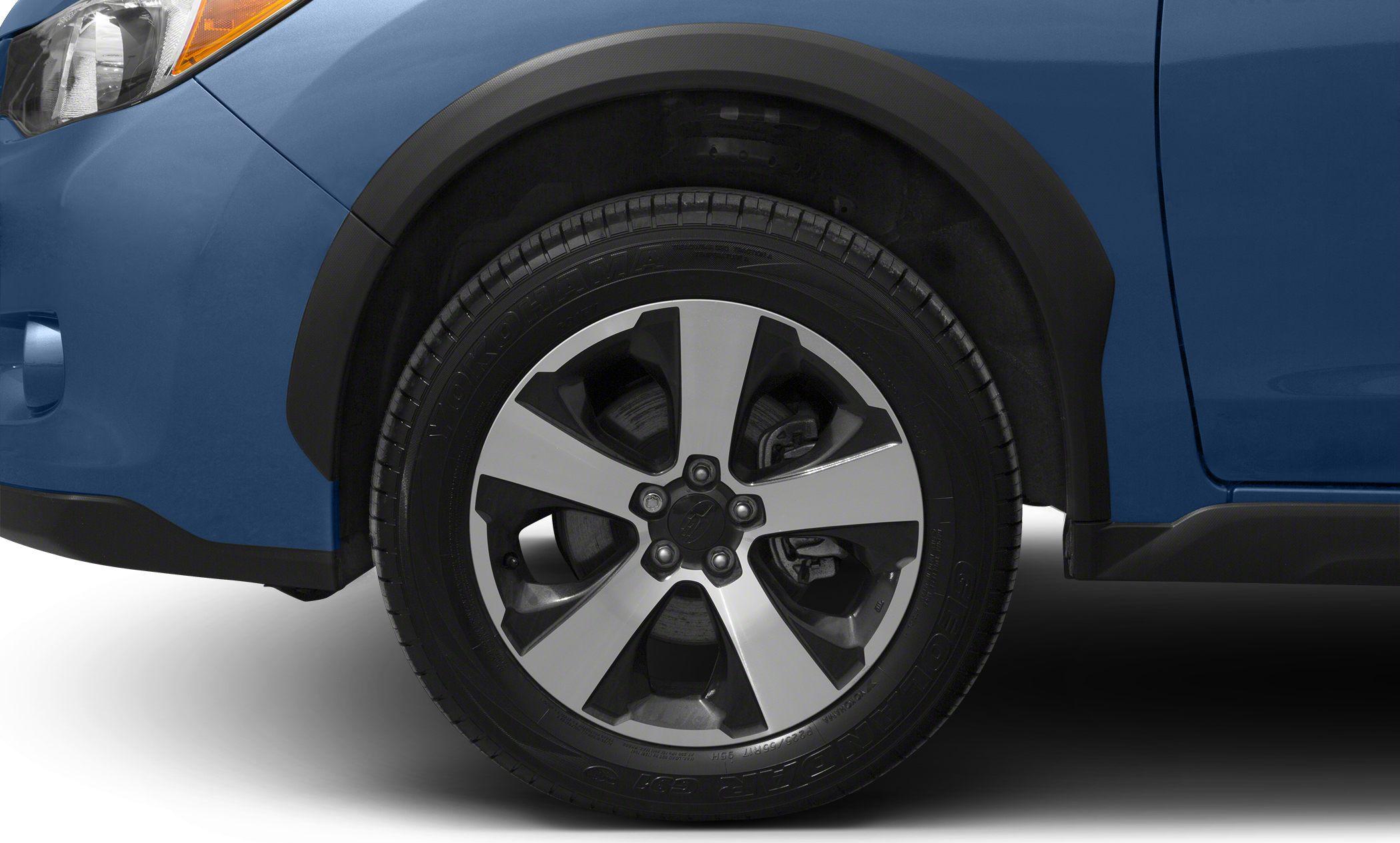 Front alloy wheel and black fender flare on blue vehicle body