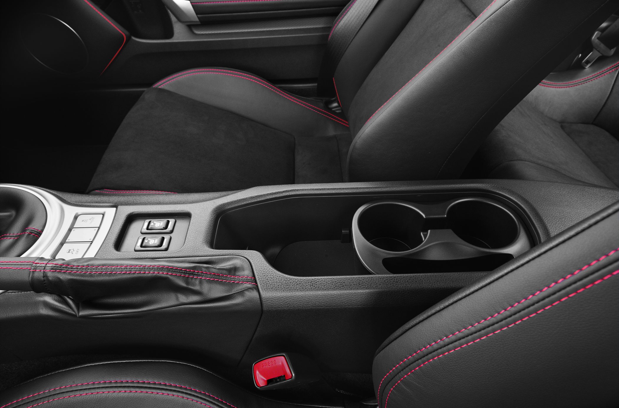 Car interior center console with red-stitched seats and cup holders