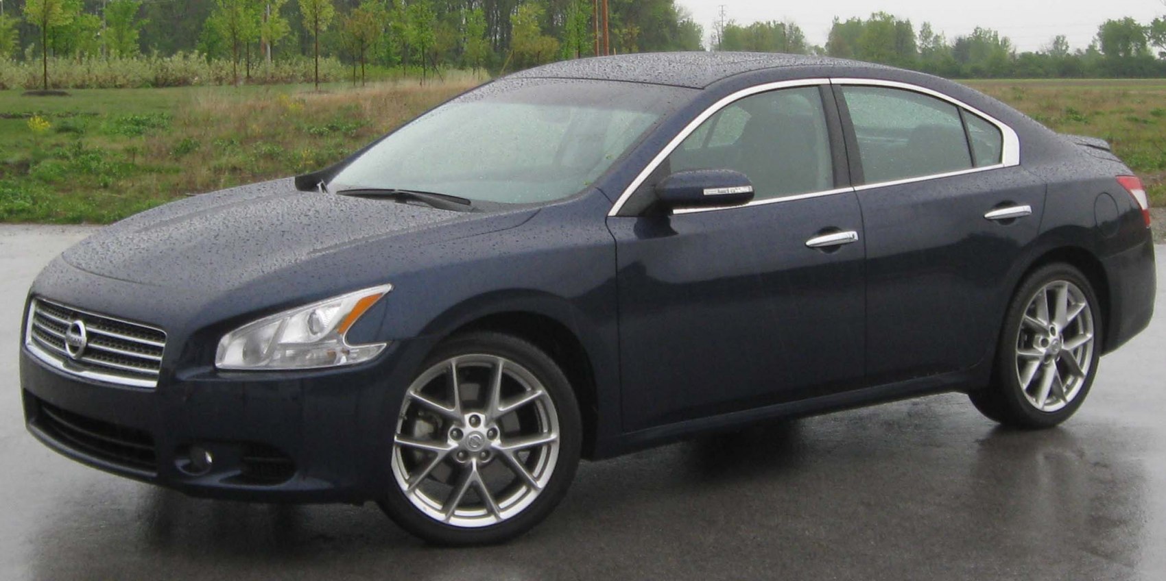 Side view of a 2009 sedan with alloy wheels and rain droplets.