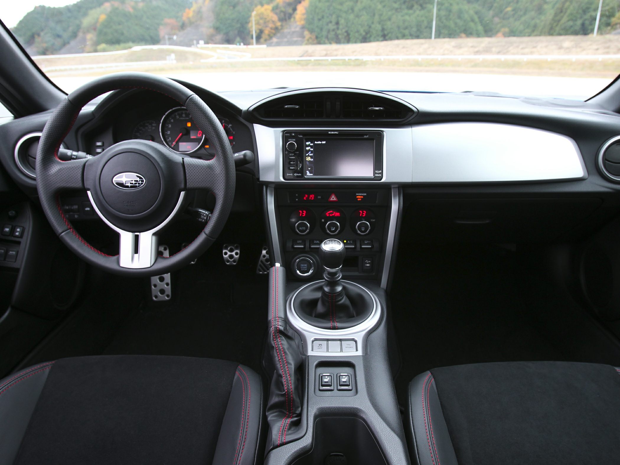 Manual transmission and sporty steering wheel with red stitching.