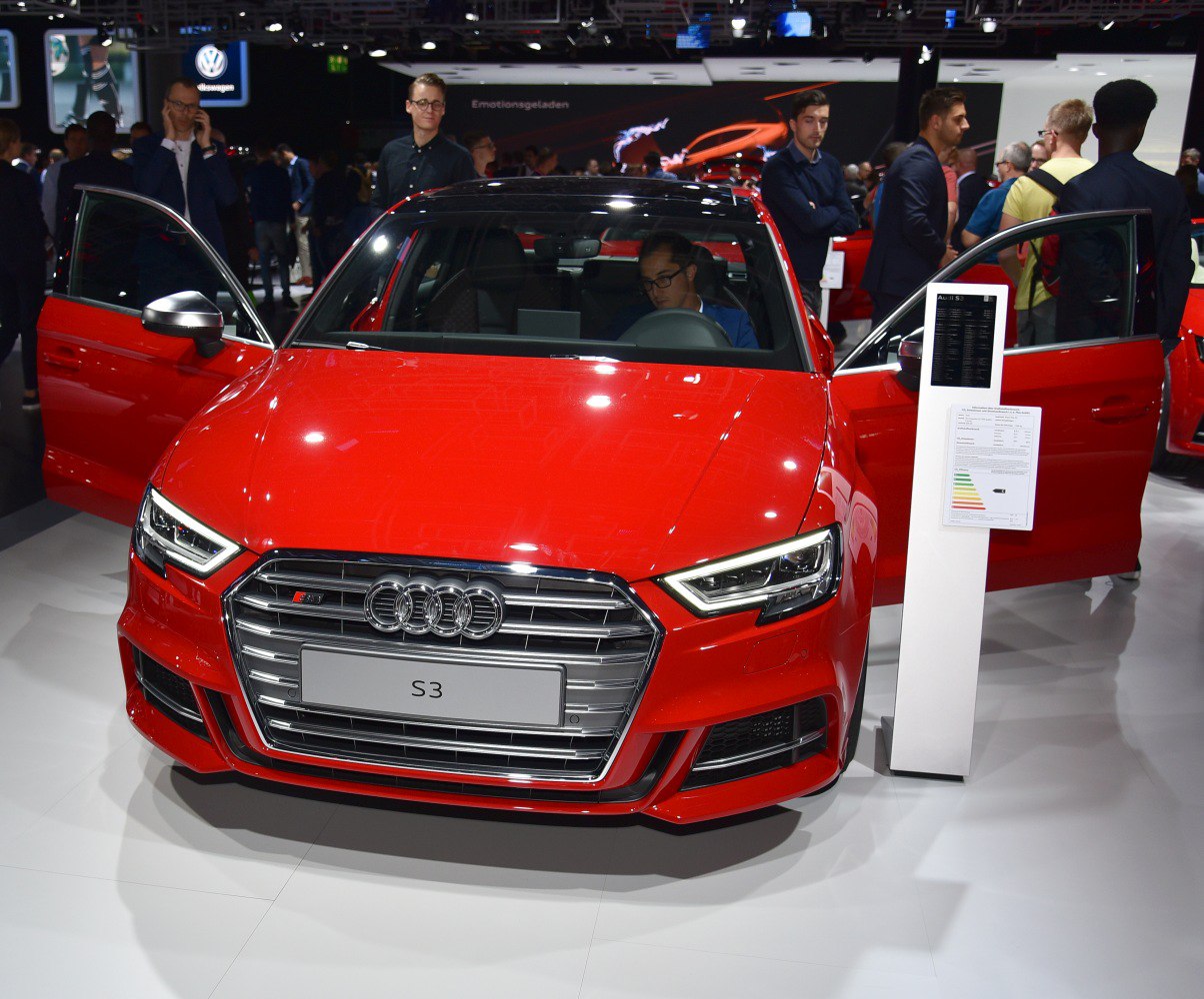 Front grille, LED headlights, and open front doors of a red sedan