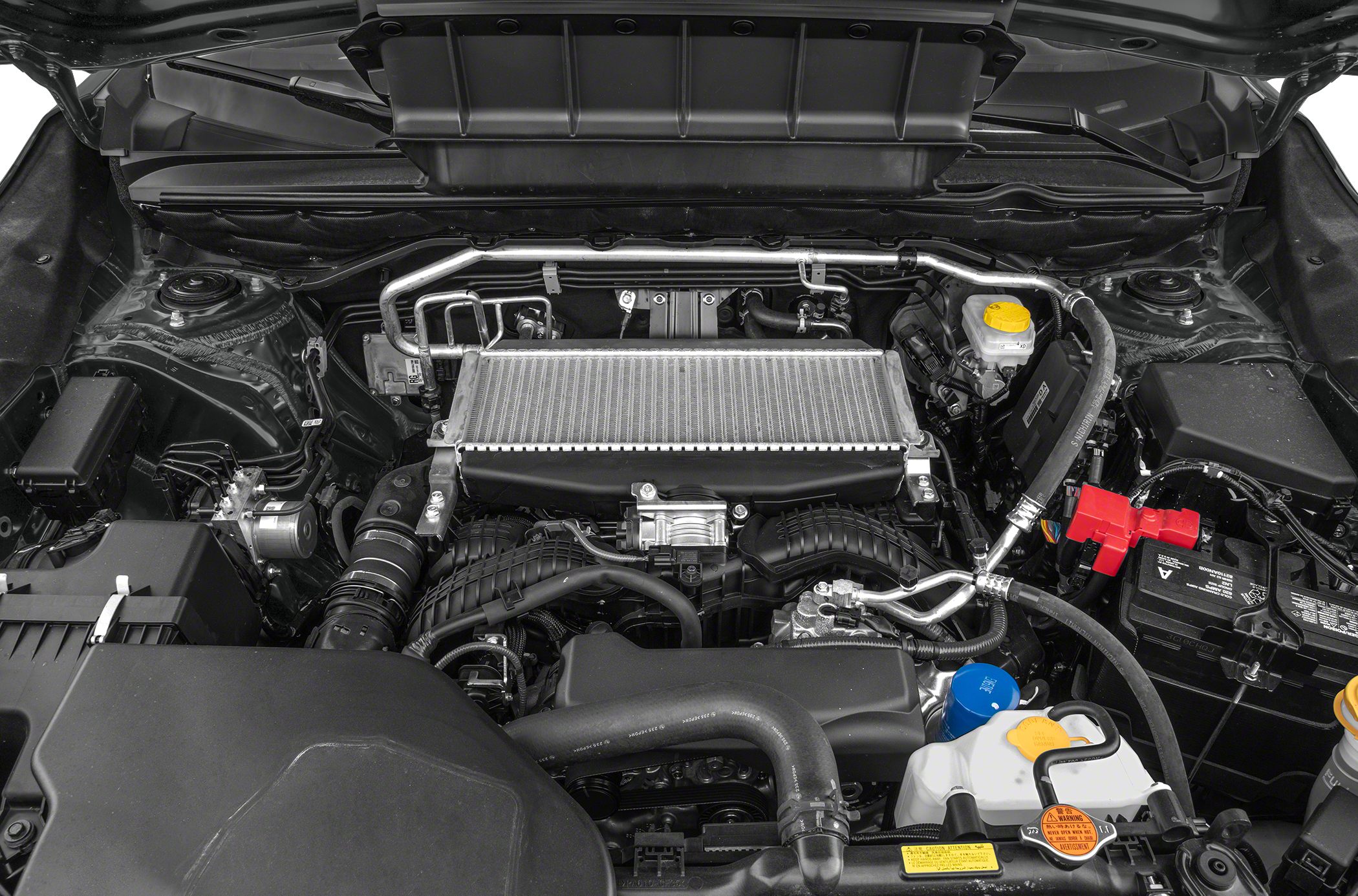 Vehicle engine bay displaying intercooler, hoses, battery, and fluid reservoirs
