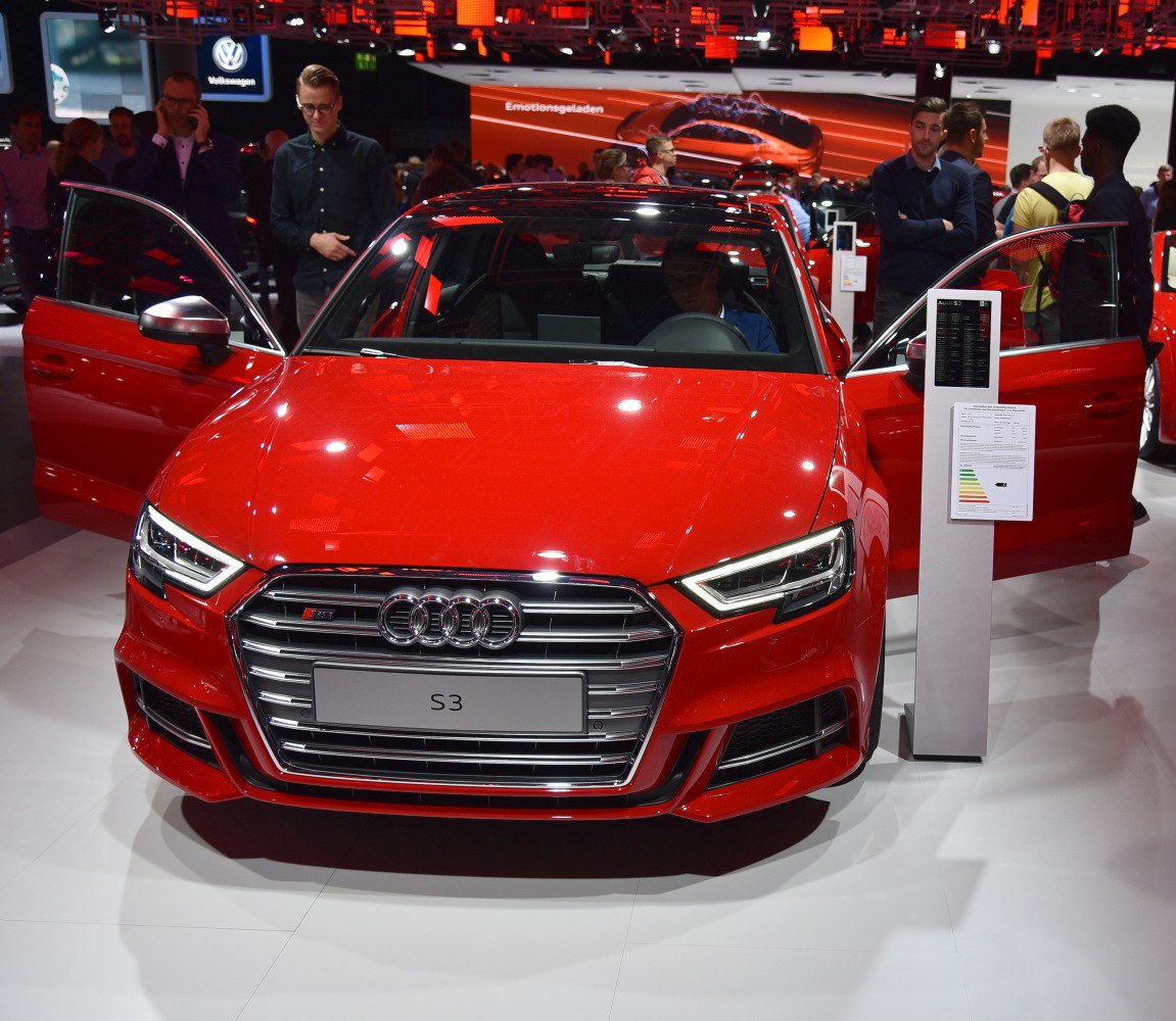 Front view of red sedan with open front doors and distinct grille