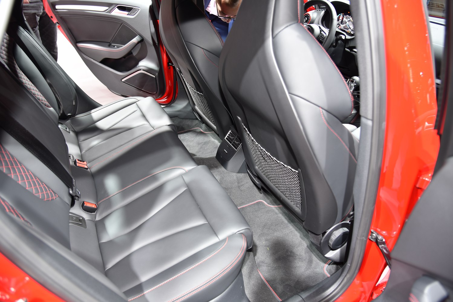 Rear black leather seats with red stitching and mesh pockets