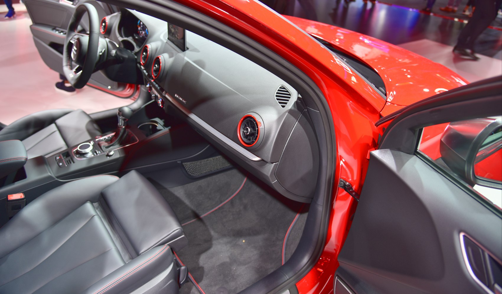 Modern car interior with dashboard, seats, and red accent vents