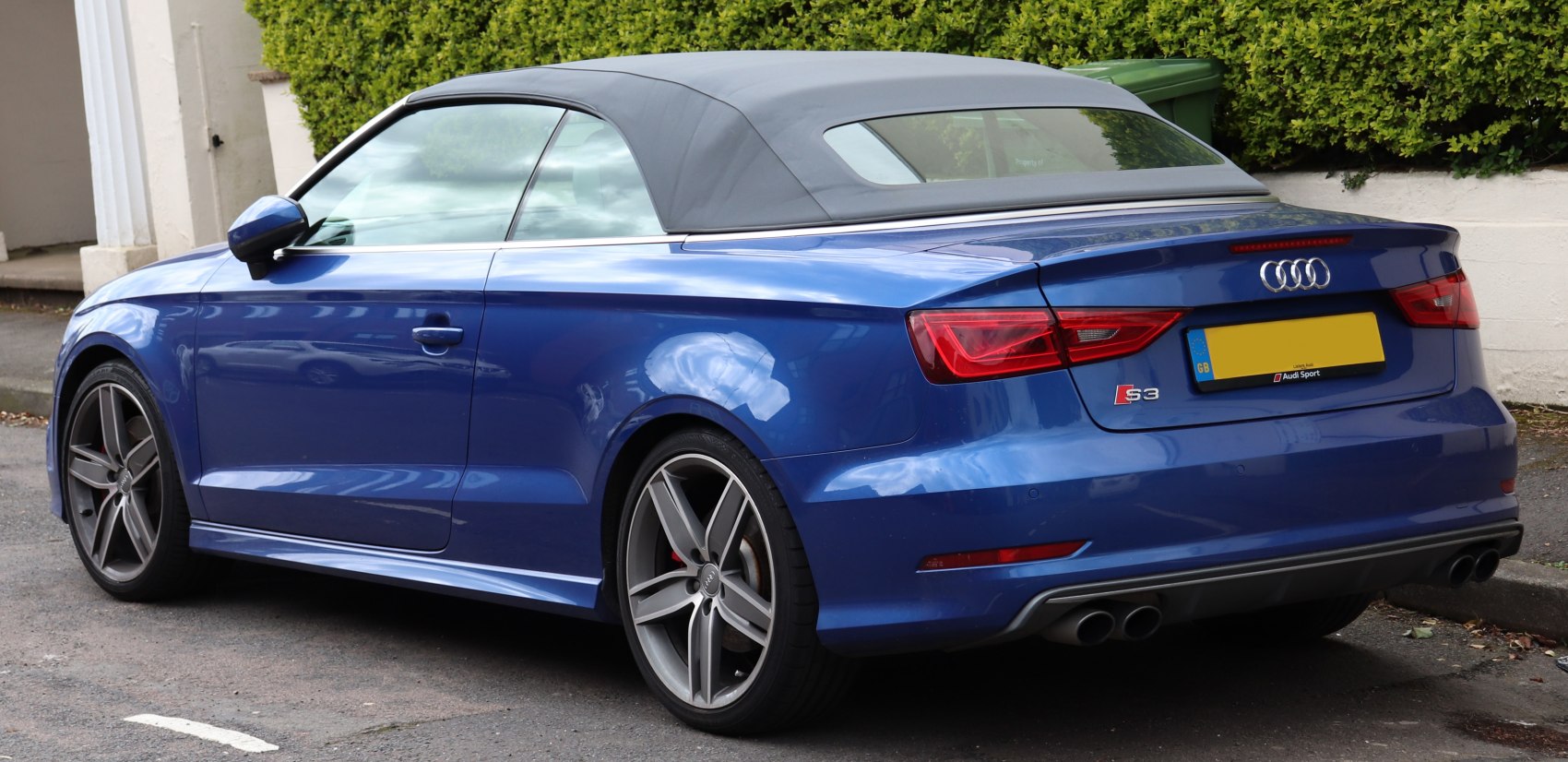 Rear side view of blue convertible with soft top and dual exhausts