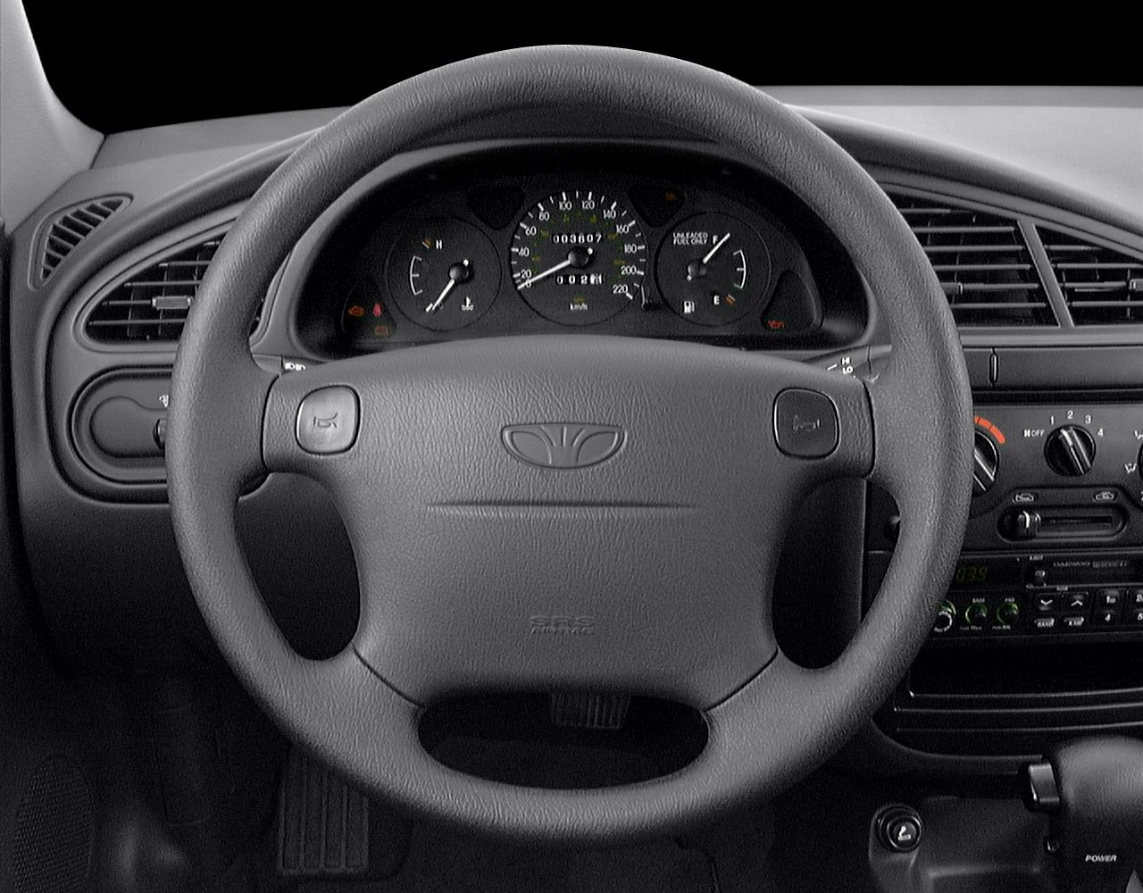 Steering wheel and dashboard with gauges, ventilation, and control knobs.