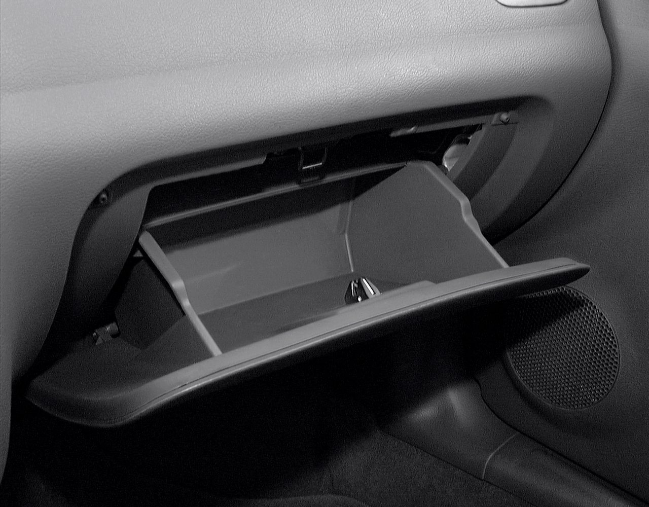 Open glove compartment showing interior storage space in vehicle dashboard.