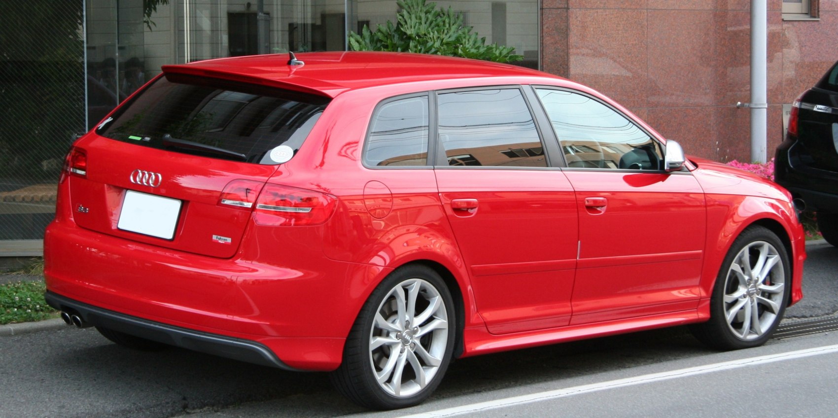 Rear-side view of red 5-door sporty hatchback with alloy wheels