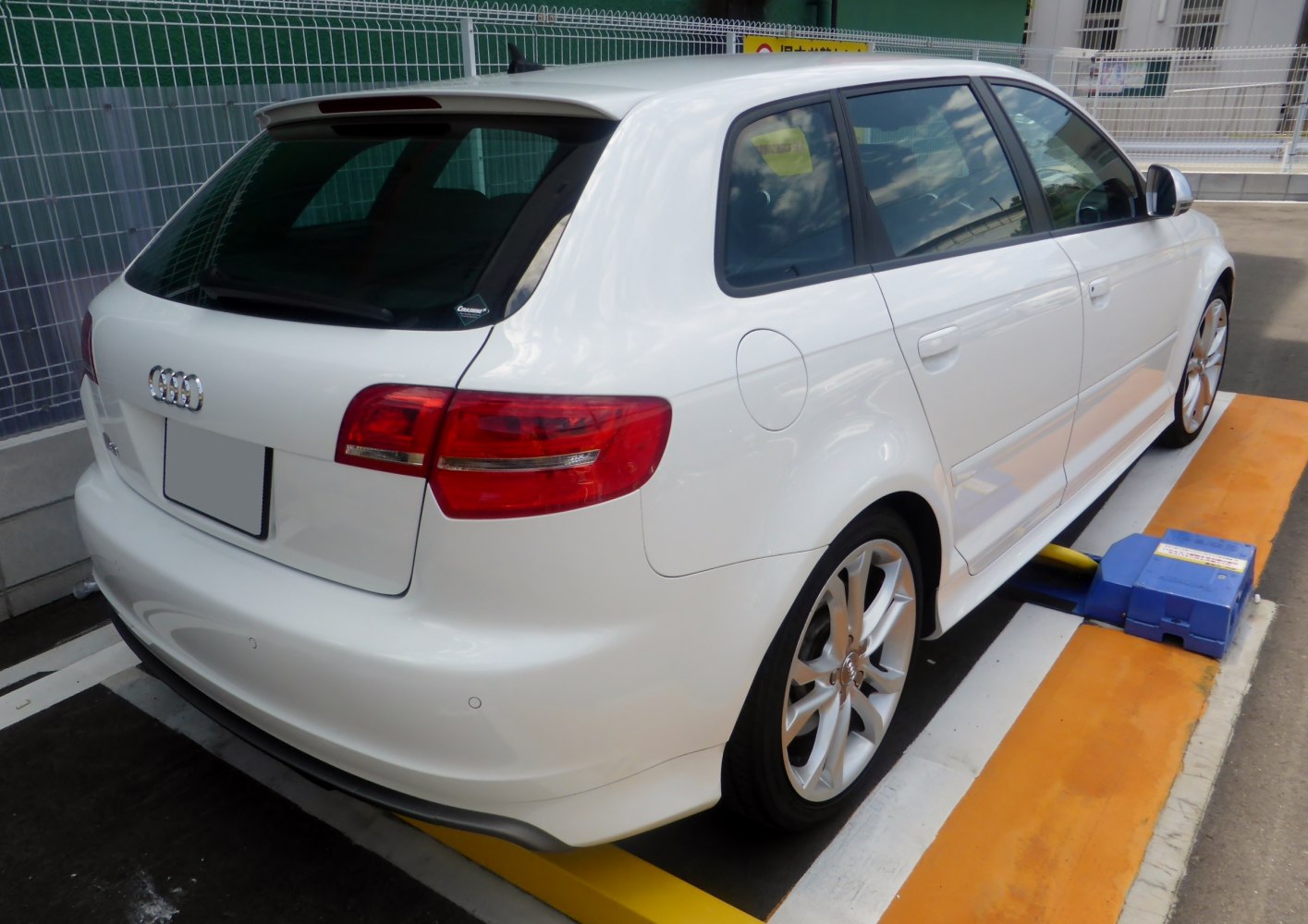 Rear view of white hatchback with spoiler and alloy wheels