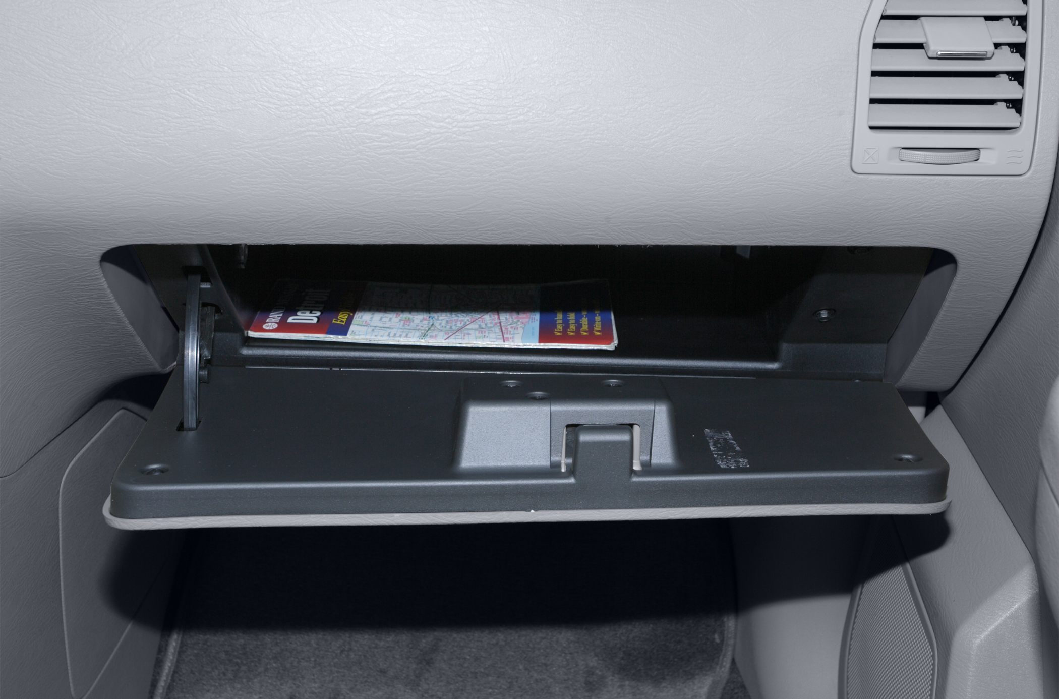 Open glove box compartment with storage space inside vehicle interior.