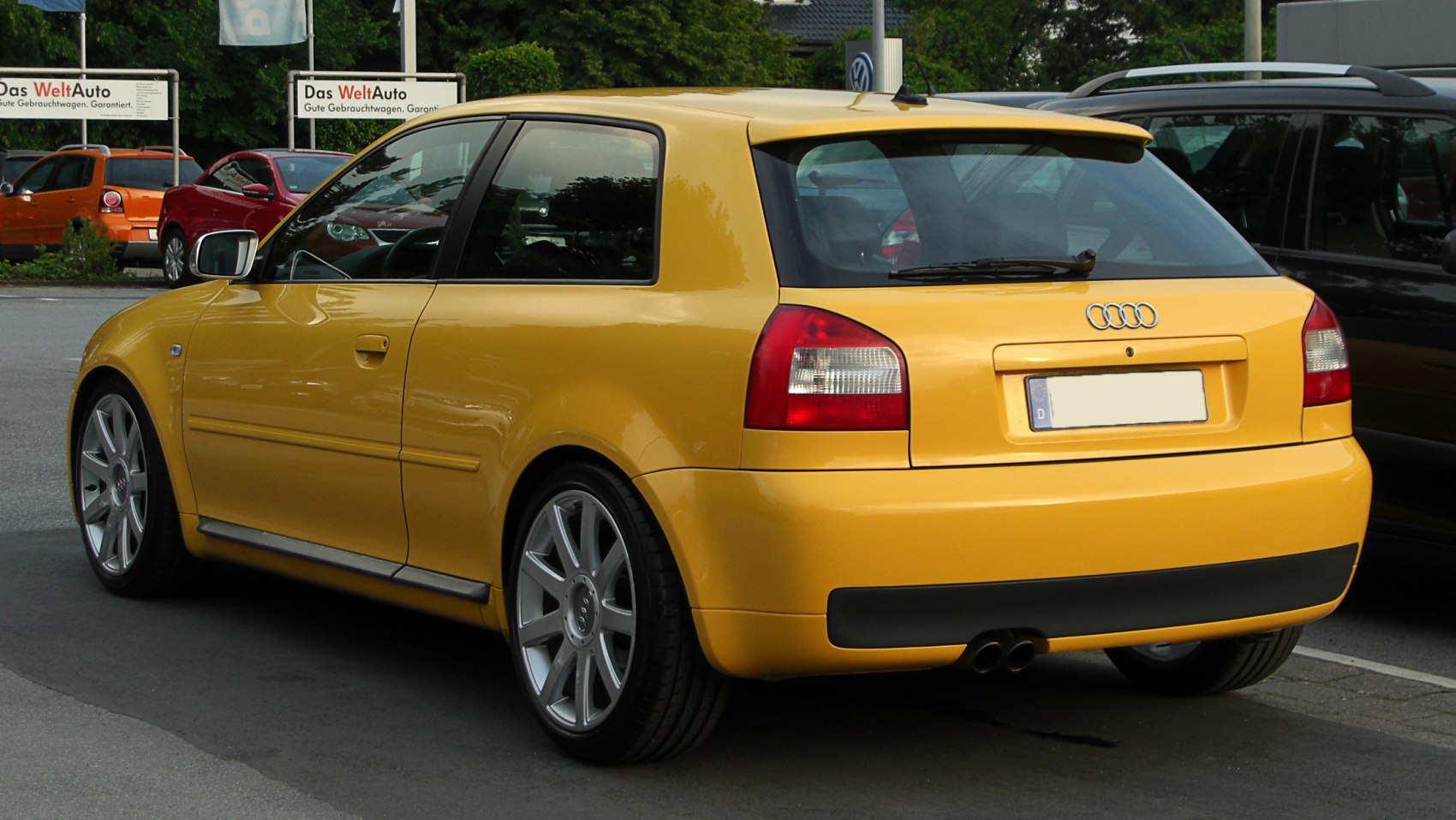 Rear-side view of a compact yellow hatchback with dual exhaust and sporty alloy wheels