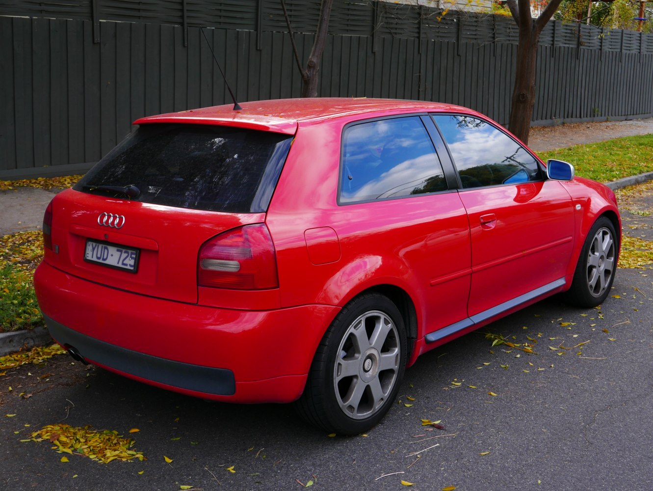 Red 3-door hatchback, alloy wheels, rear spoiler, tinted windows.