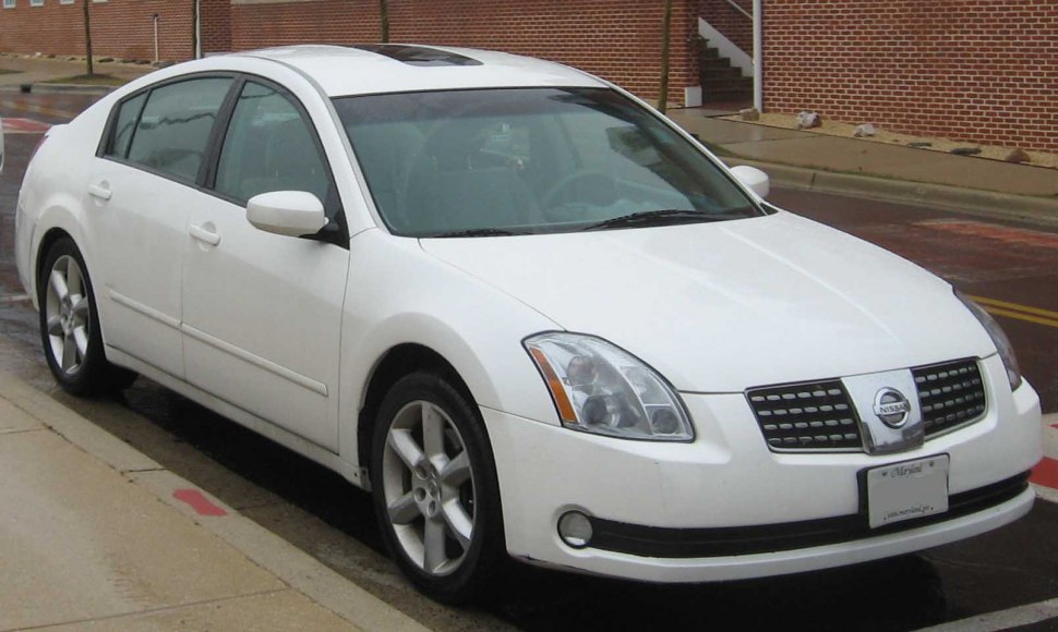 White sedan with alloy wheels and sunroof parked on street.