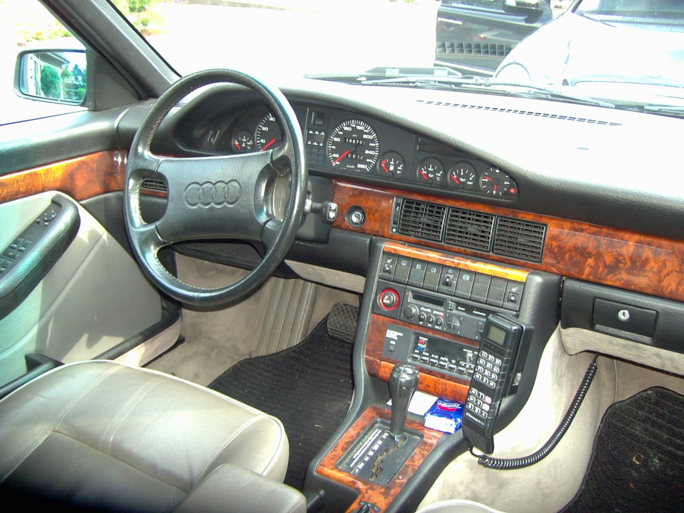 Classic wood trim interior with analog gauges and vintage mobile phone.