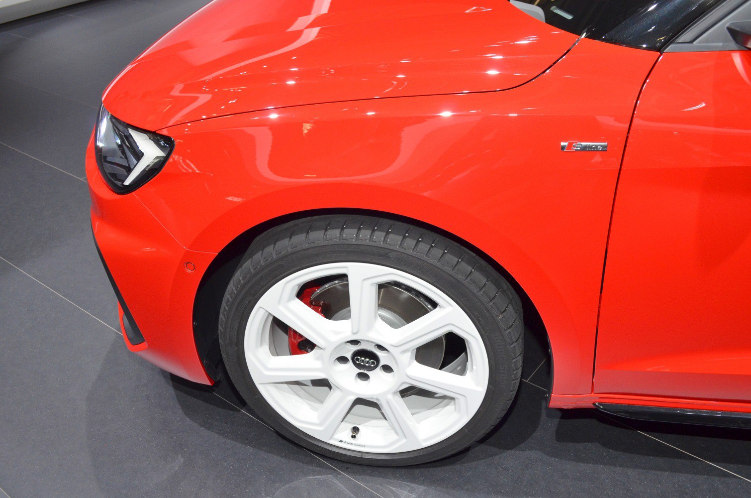 White alloy wheel, red brake caliper, and sharp front headlight