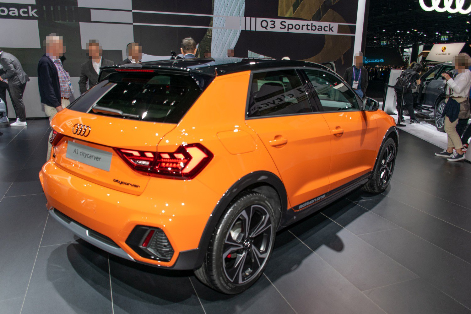 Rear side view of orange compact hatchback with sporty wheels and unique taillights