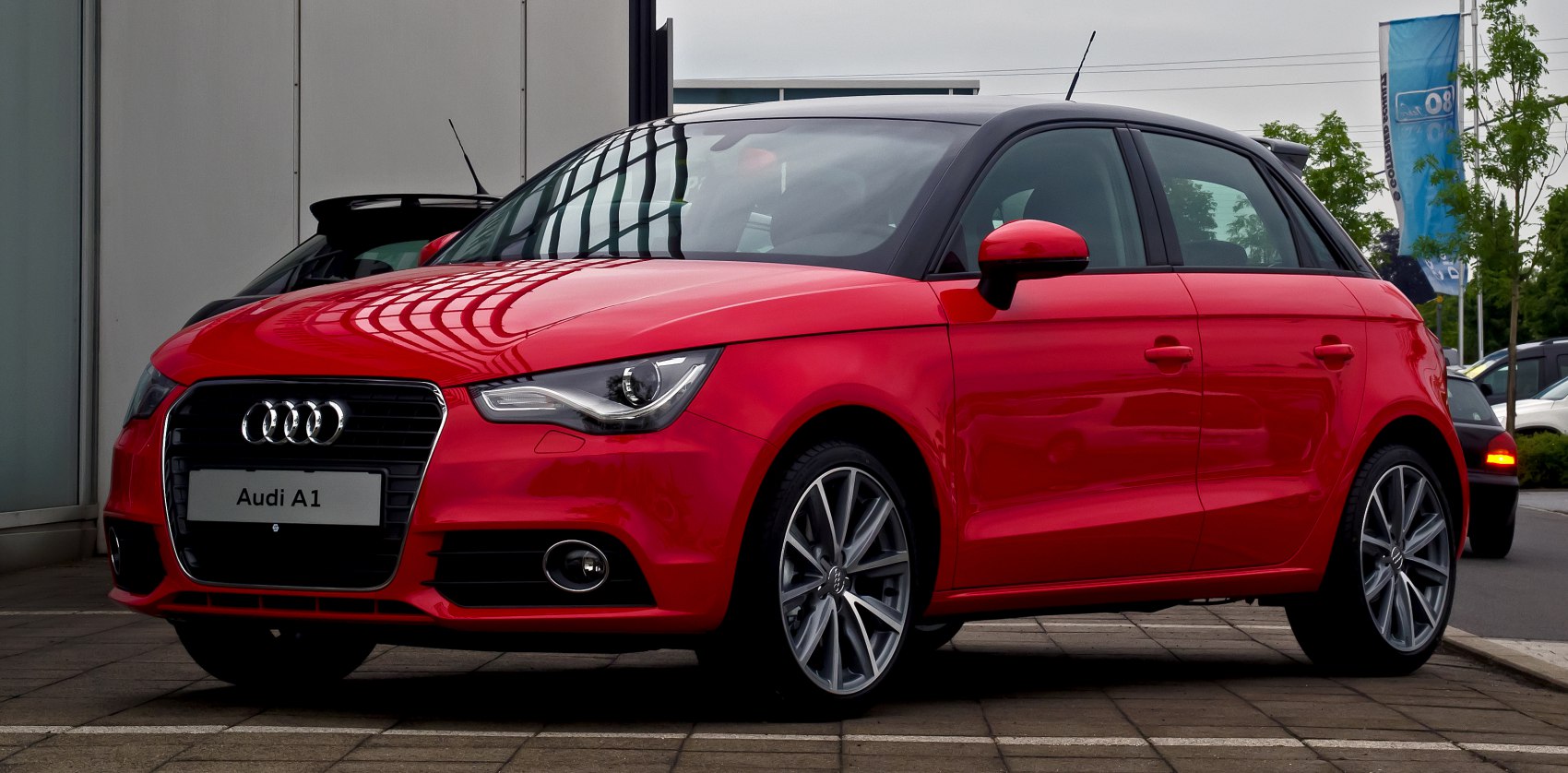 Red hatchback with sleek headlights and sporty rims, front side view