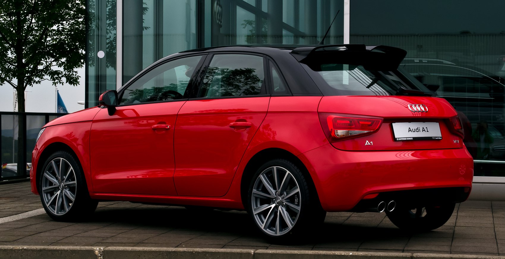 Red five-door hatchback rear-side view with dual exhaust and sporty alloy wheels