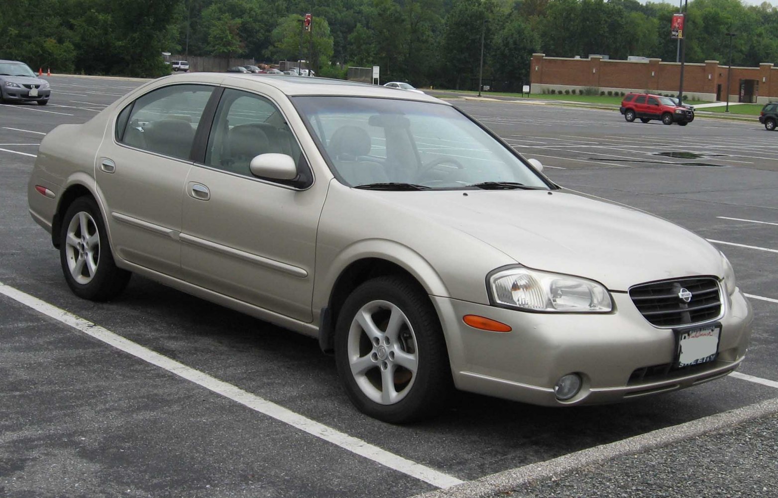 Front side view of beige sedan with alloy wheels in parking lot