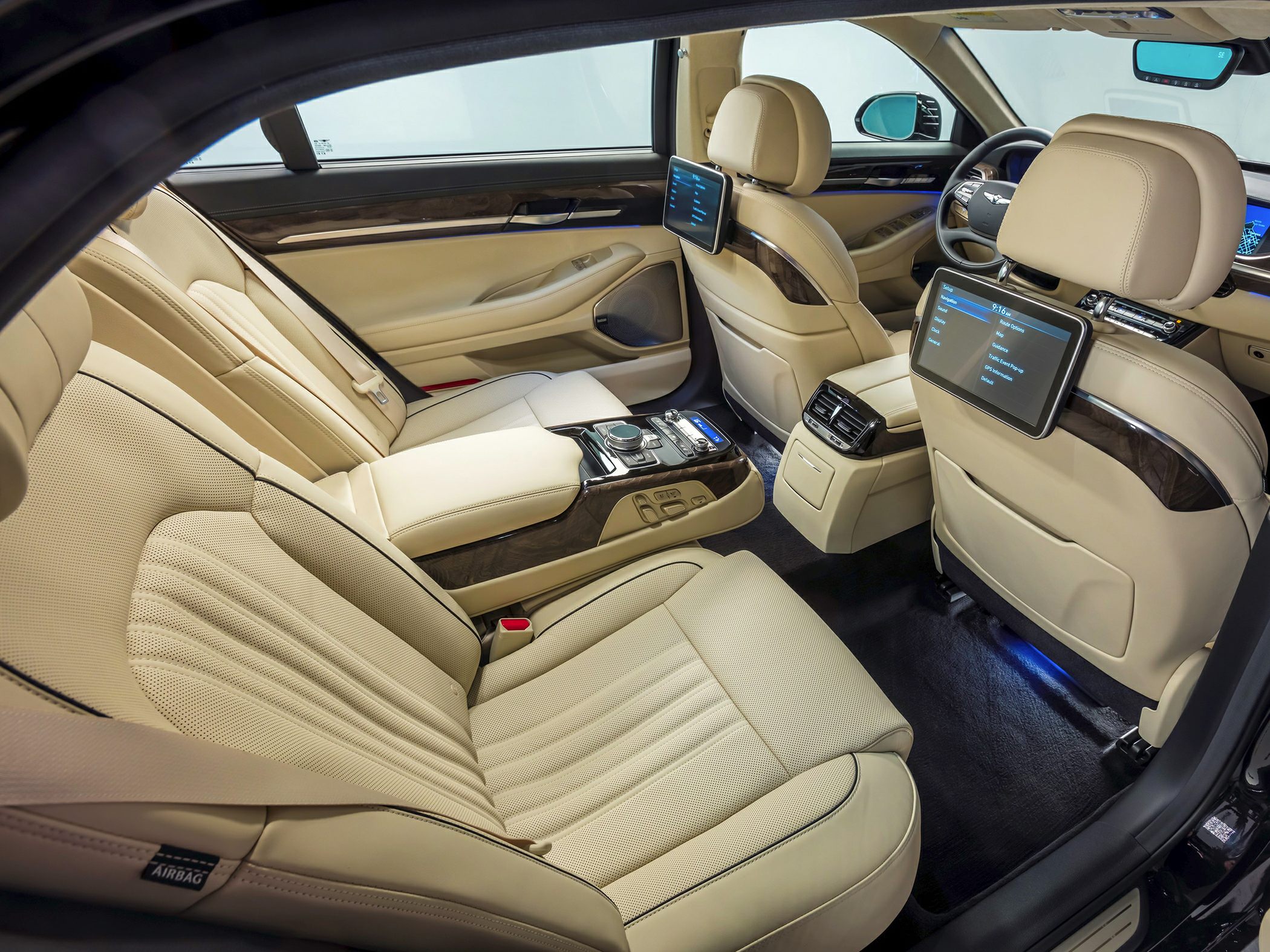 Luxurious beige rear passenger seats with entertainment screens and central control panel