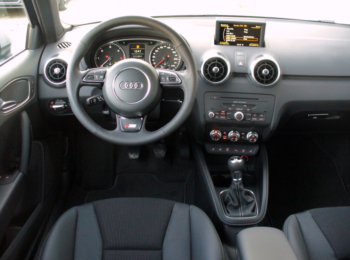 Audi car interior with steering wheel, dashboard, and manual gear shift