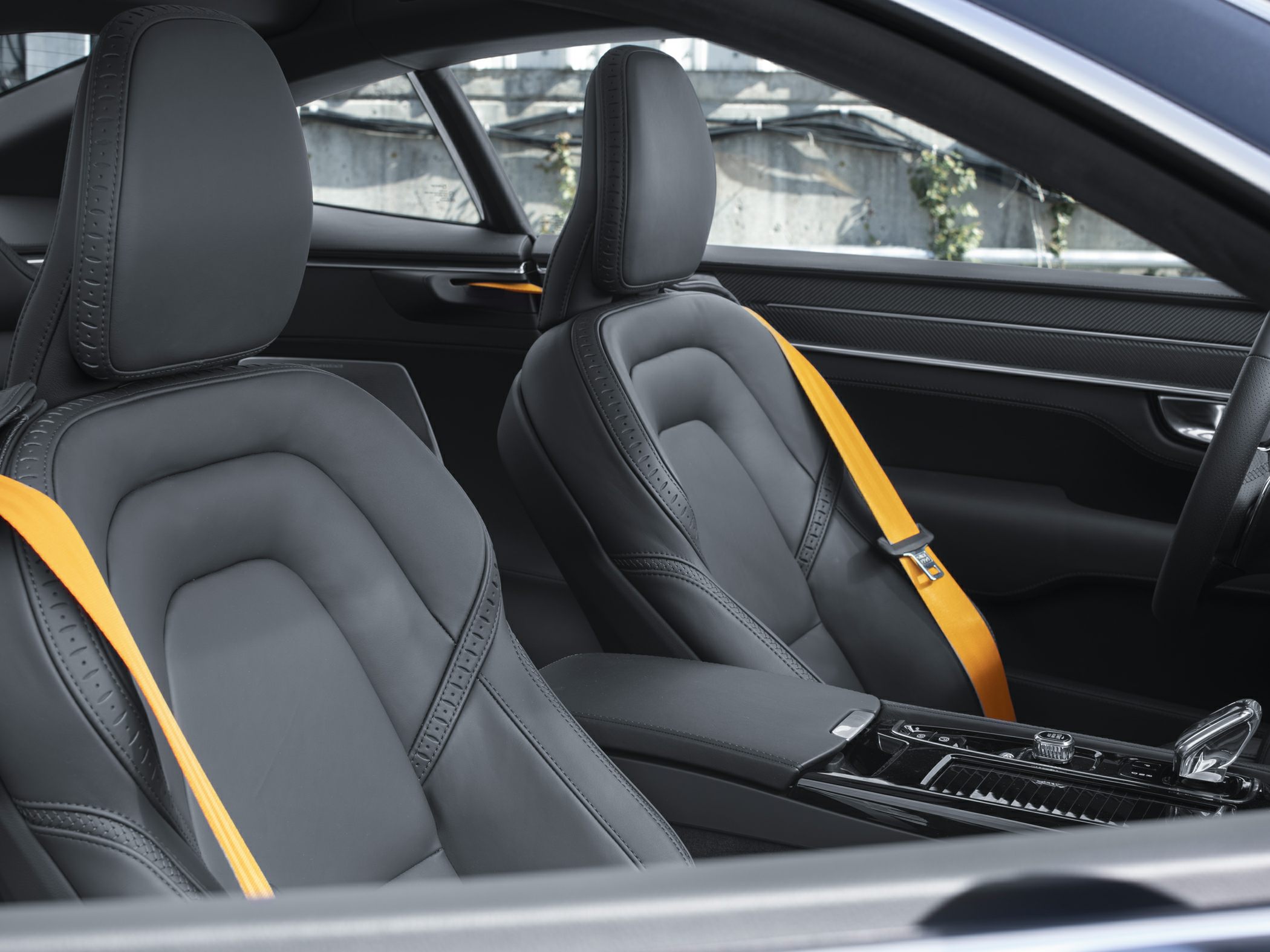 Black leather car seats with detailed stitching and yellow seatbelts